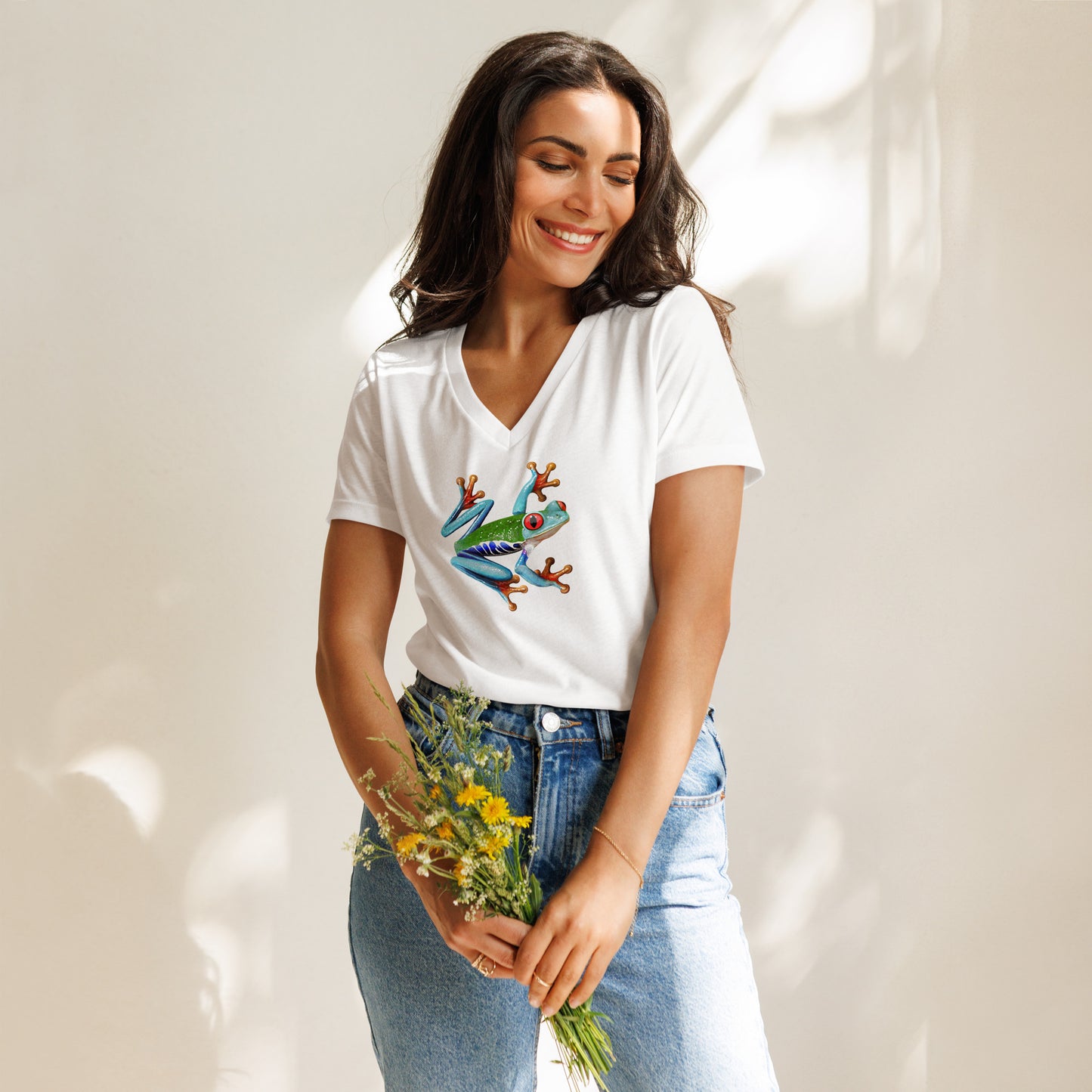 Female model wearing the v-neck anura Sigma womens relaxed t-shirt in white from the front holding flowers.