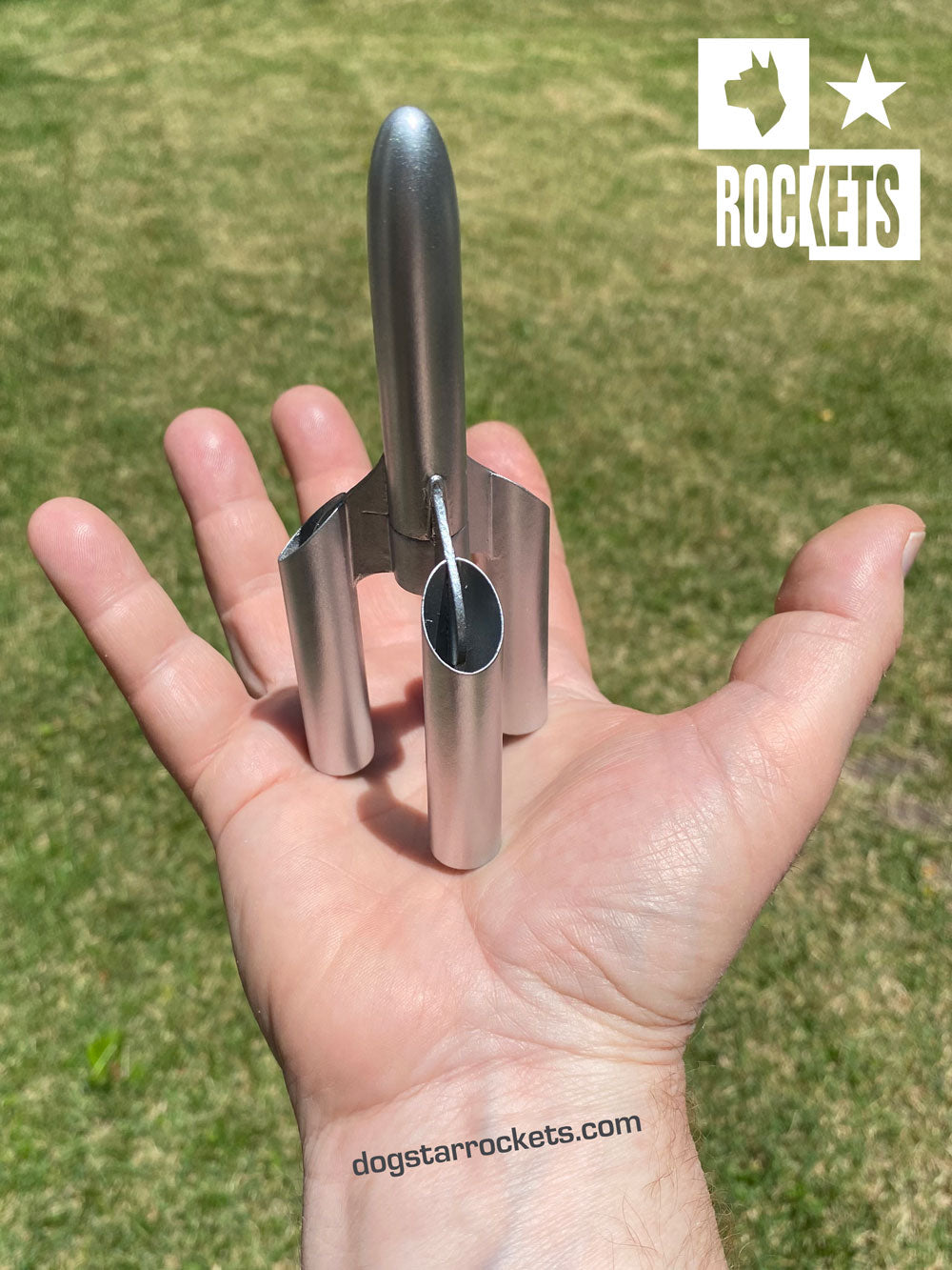 Nano Orchid Model Rocket painted silver and standing in the palm of a hand.